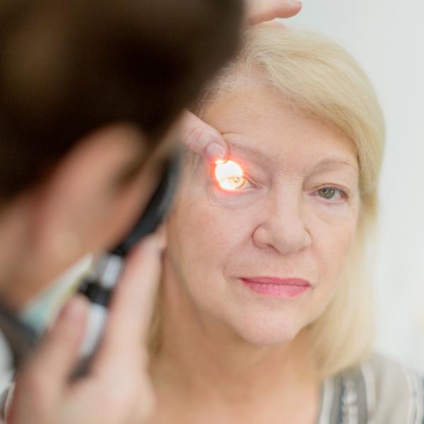 Woman receiving eye exam with light shining in her eye