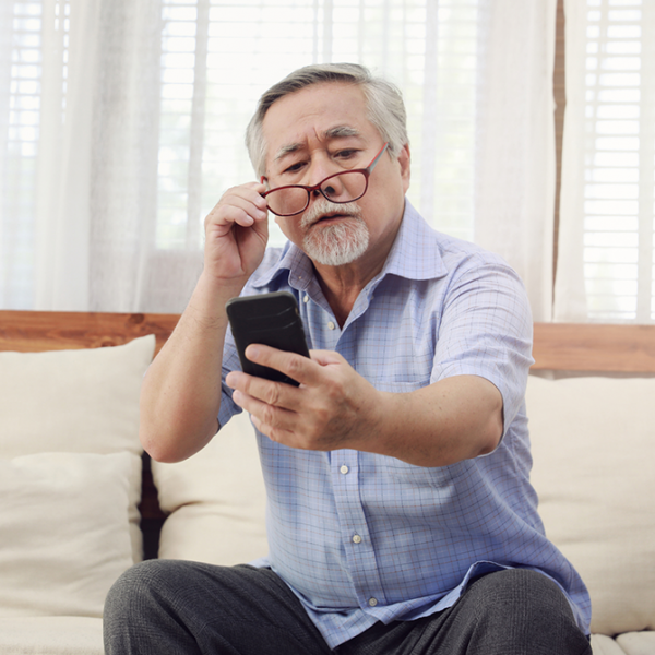 A man with presbyopia holding a phone away from his face so he can see it.