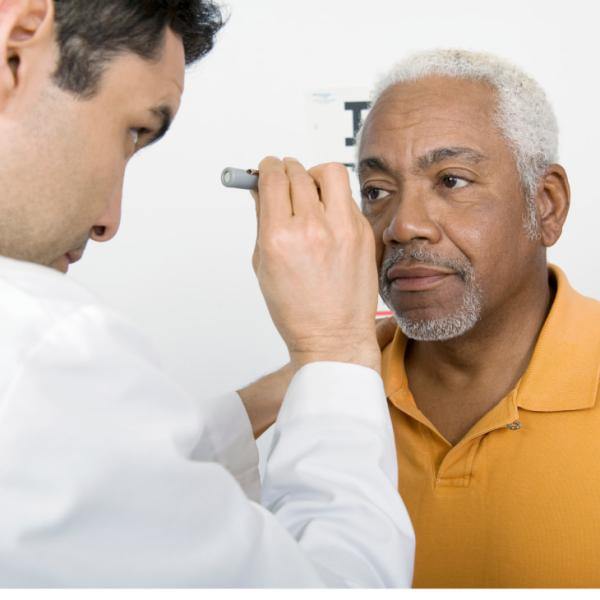Un hombre recibe un examen ocular, con una luz enfocada en su ojo.