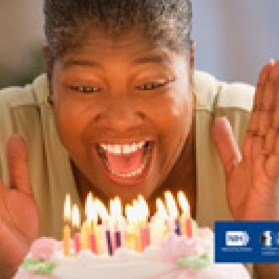 Woman smiling at the cake with burning candles.   NIH,  National Eye Institute. NEHEP, National Eye Health Education Program.