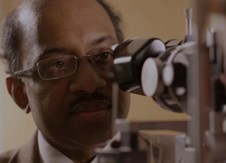 A doctor looks into a slit lamp