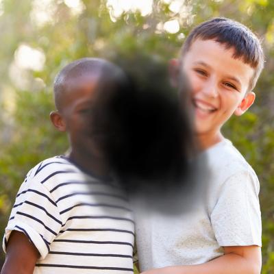 Two boys smile at camera. Dark spot in center of image represents vision loss from AMD.