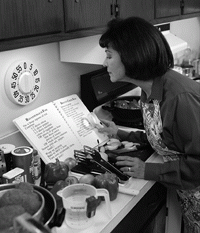 Una mujer lee una receta y prepara la comida