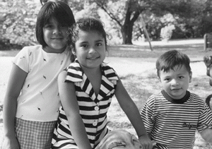 Una foto de tres niños sonriendo. La foto se ve clara y muestra la visión normal.