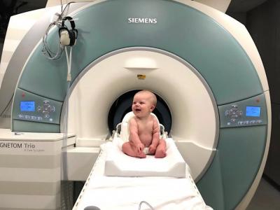 A baby sitting in front of an MRI machine