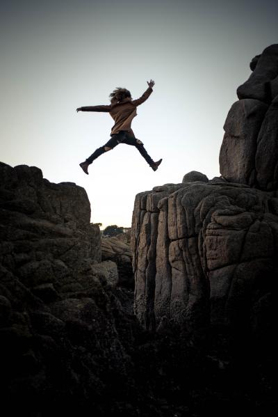 person leaping across rock crevice. Credit: Sammie Vasquez Upsplash