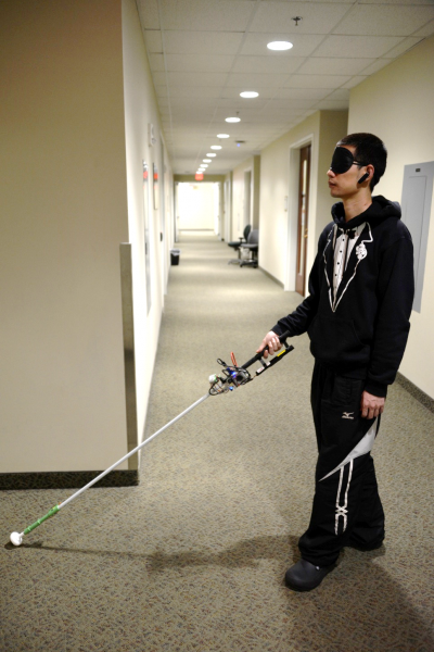 Blindfolded scientist tests robotic cane in a hallway