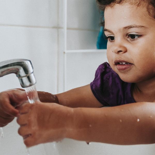 طفل صغير يغسل يديه في الحوض.