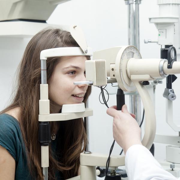 Girl has her eyes examined using a slit lamp