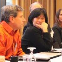 Two women panelists look at male colleague as he speaks