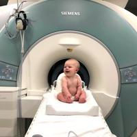 A baby sitting in front of an MRI machine