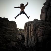 person leaping across rock crevice. Credit: Sammie Vasquez Upsplash