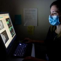 Scientist examines scientific images on a screen in a dark room.